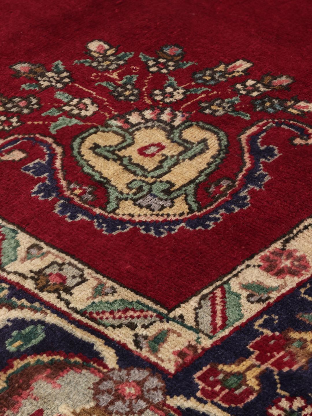 Handmade Tabriz rug with a red field and intricate blue floral medallion from the Middle East