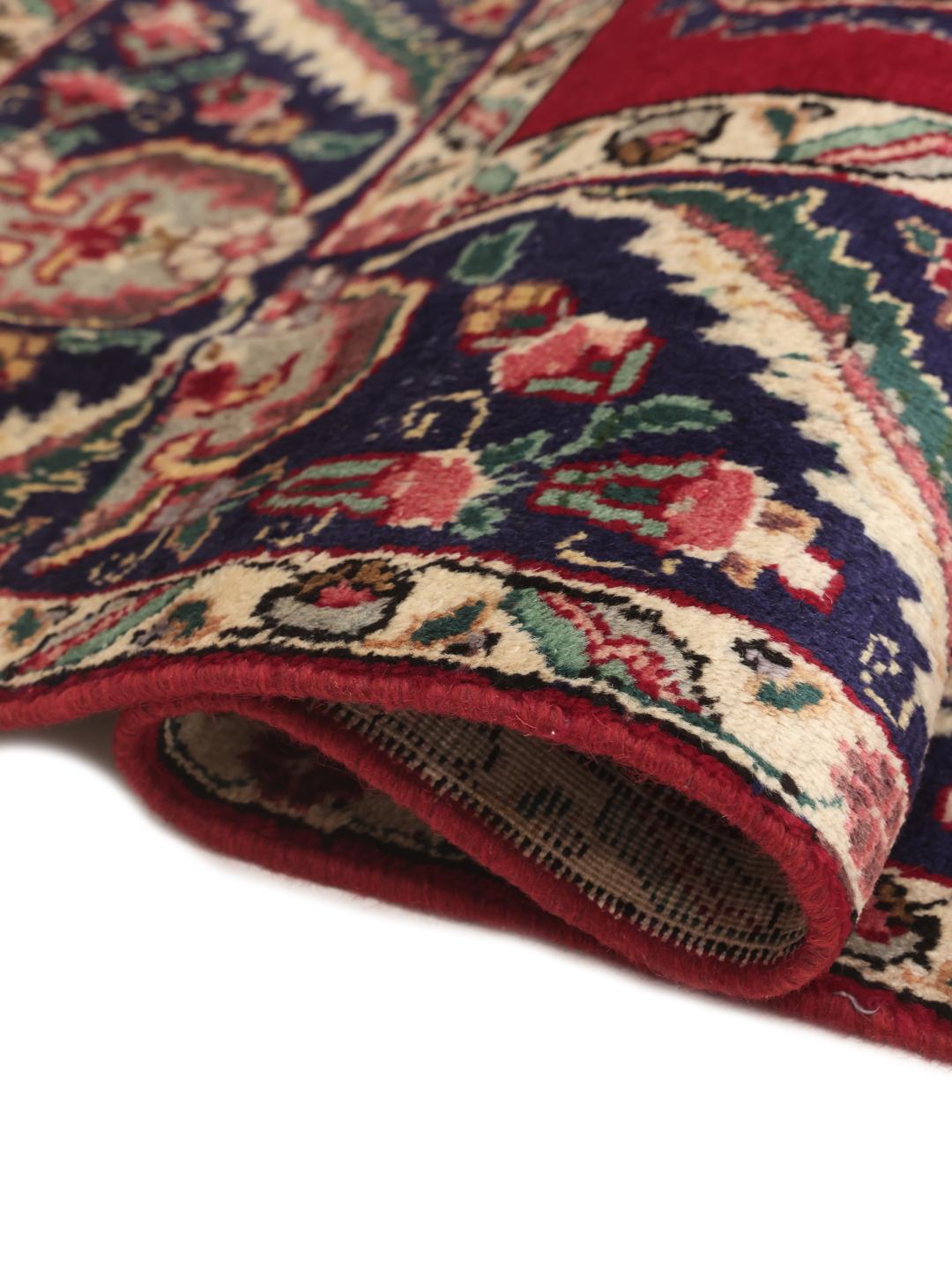 Handmade Tabriz rug with a red field and intricate blue floral medallion from the Middle East