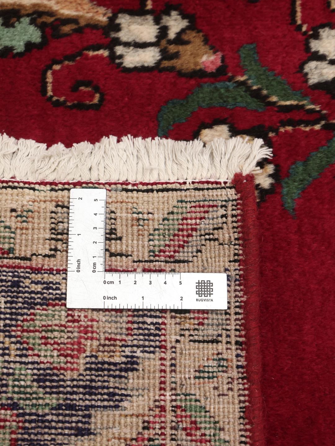 Handmade Tabriz rug with a red field and intricate blue floral medallion from the Middle East