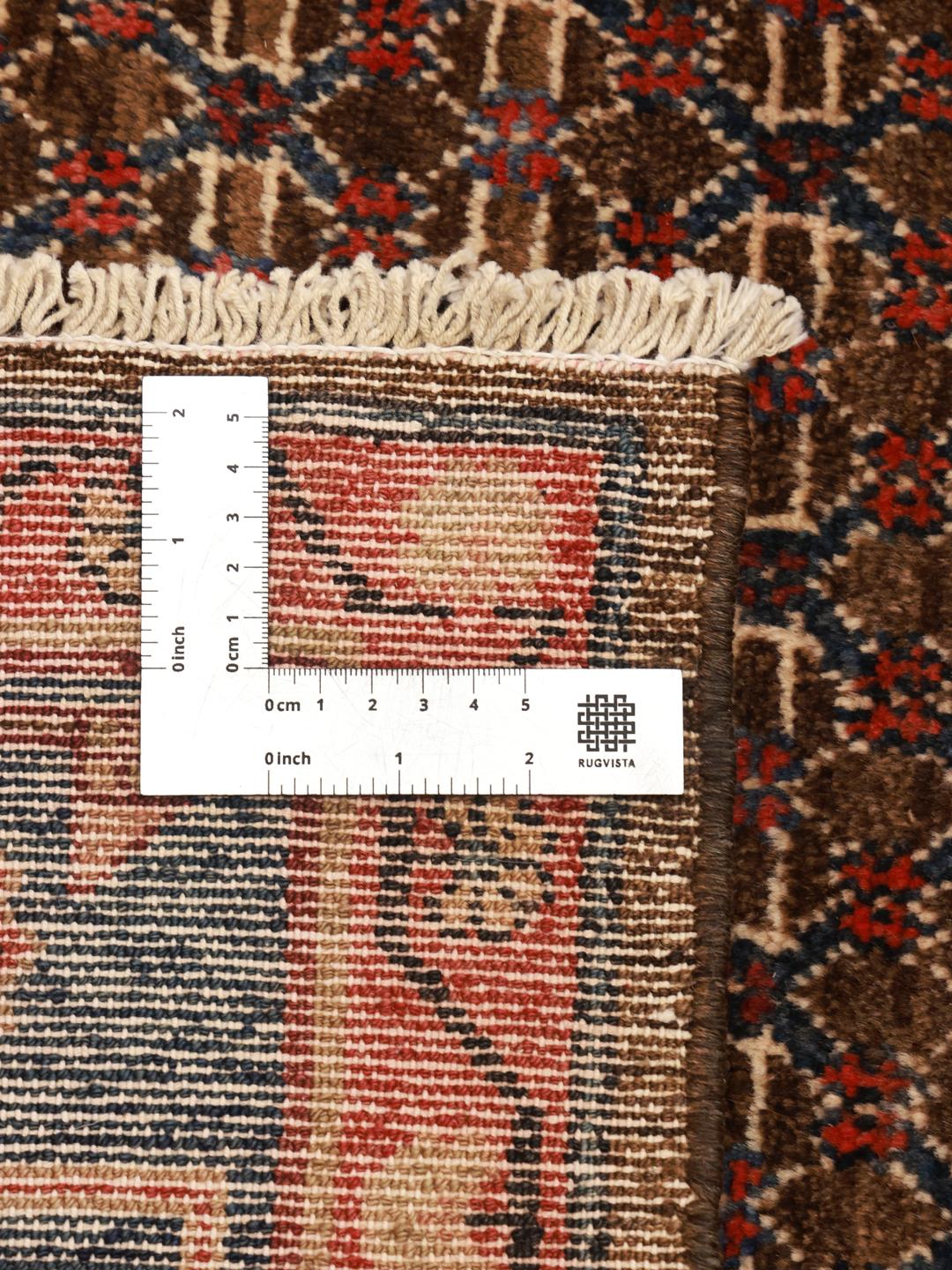 Een handgeknoopt Koliai tapijt met ingewikkelde geometrische motieven in diepblauw, rood en bruin.