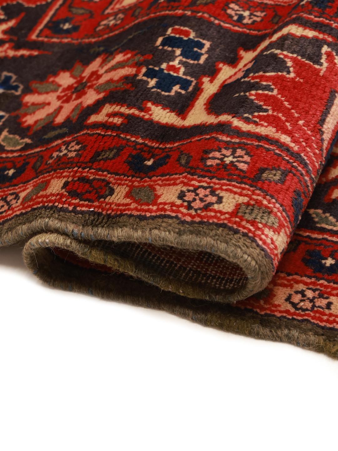 Een handgeknoopt Koliai-tapijt uit het Midden-Oosten in dieprode en beige tinten.