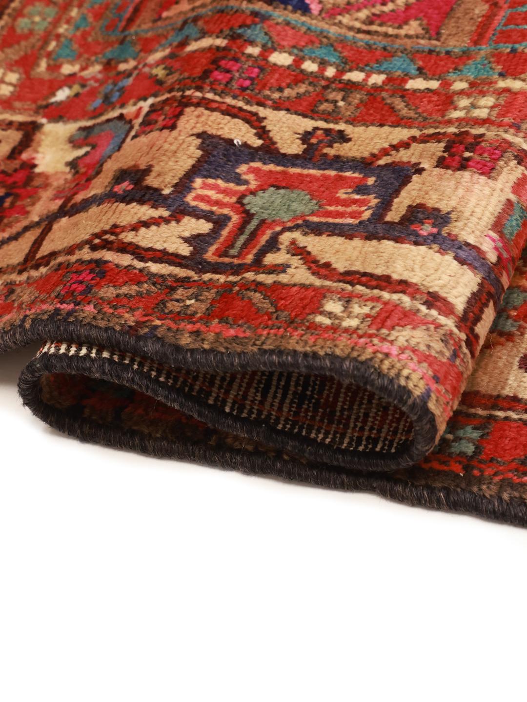 A vibrant hand-knotted rug from the Middle East with a deep red field and ornate tribal motifs.