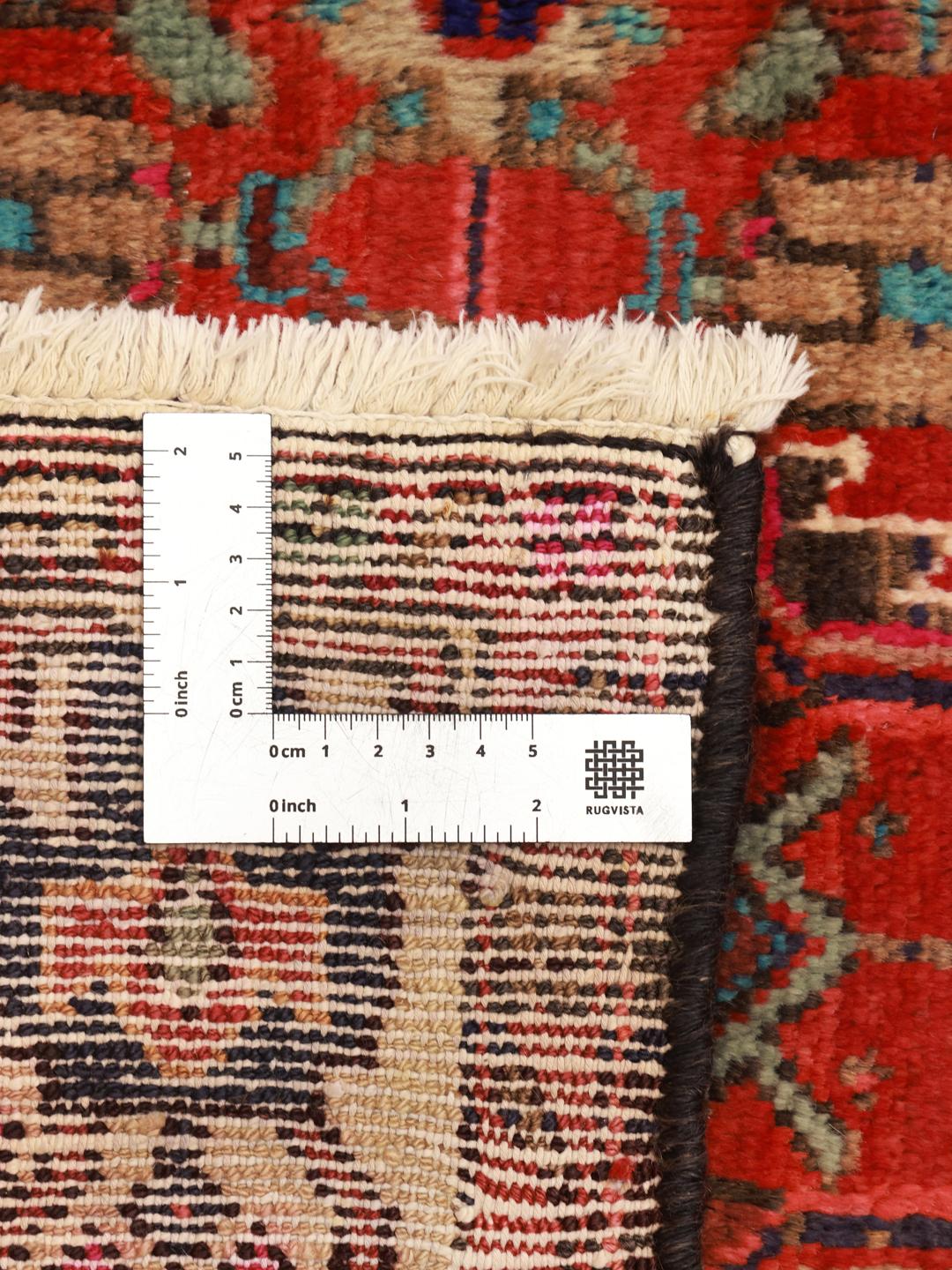 A vibrant hand-knotted rug from the Middle East with a deep red field and ornate tribal motifs.