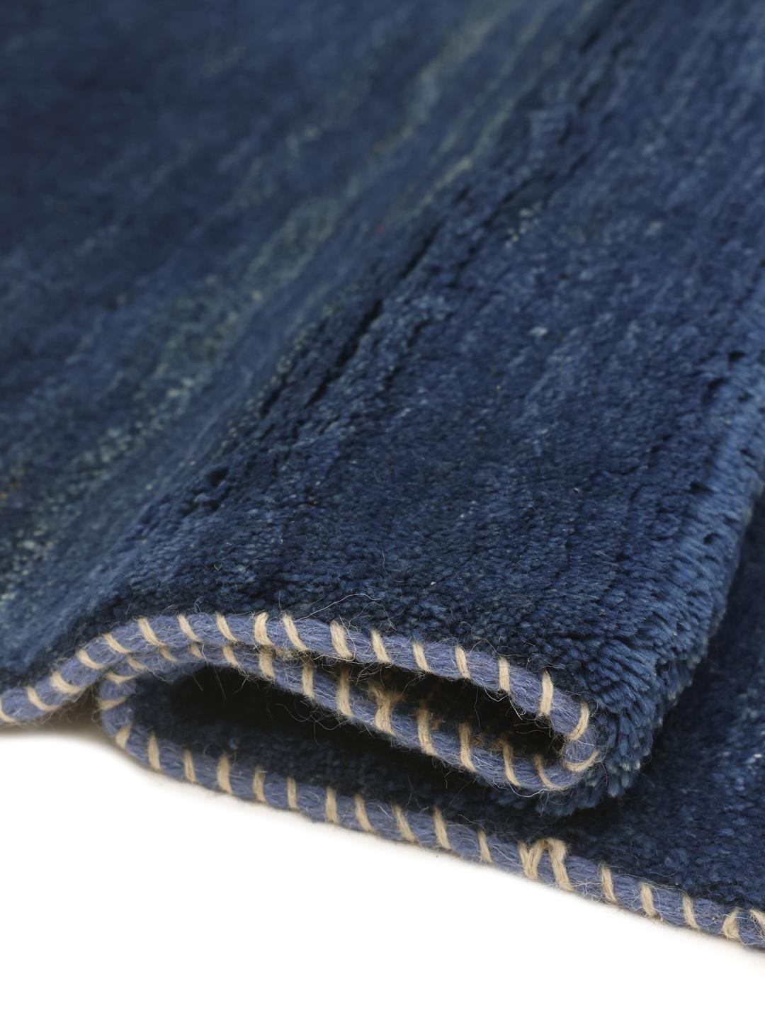 Een diepblauw handgeknoopt Gabbeh-tapijt uit het Midden-Oosten met een zachte wollen textuur.