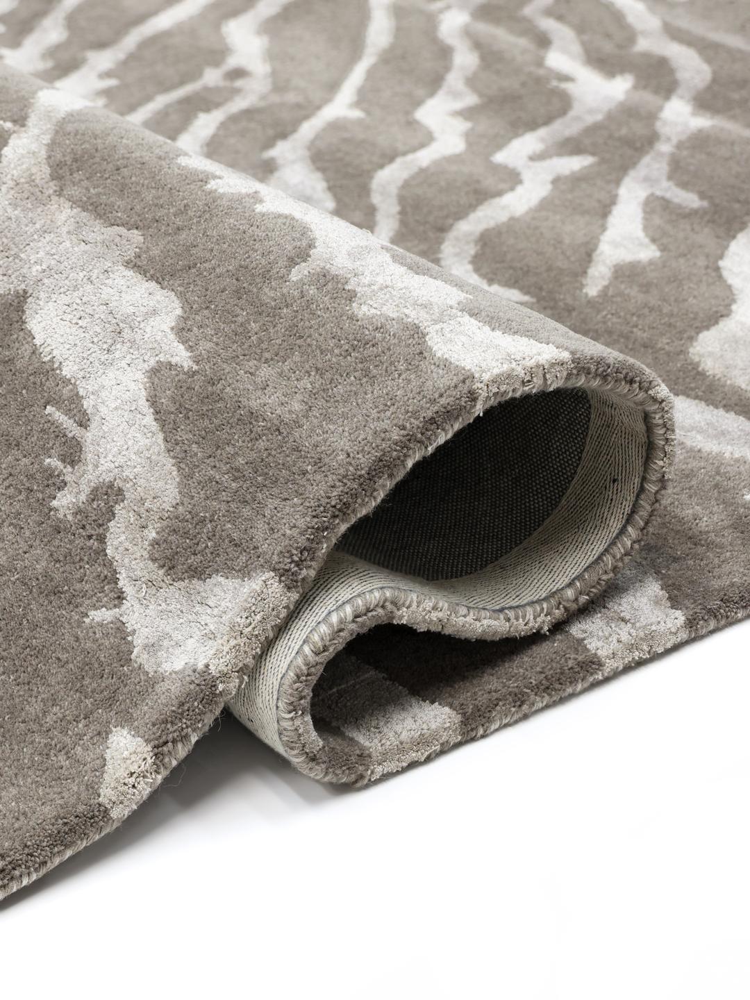 Un tapis rectangulaire avec un motif inspiré des animaux dans des tons grège et gris clair.