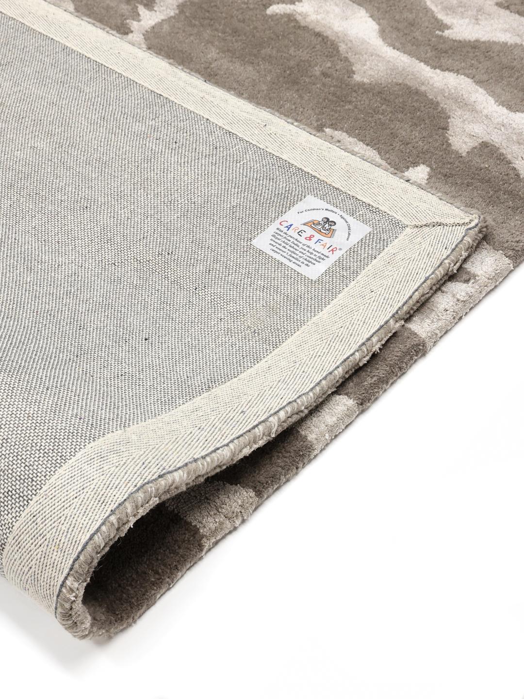 Un tapis rectangulaire avec un motif inspiré des animaux dans des tons grège et gris clair.