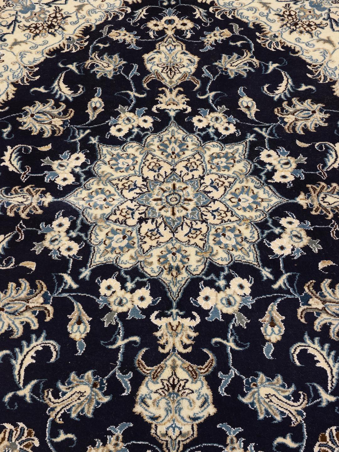 A hand-knotted rug from the Middle East with a dark-blue field and floral patterns.