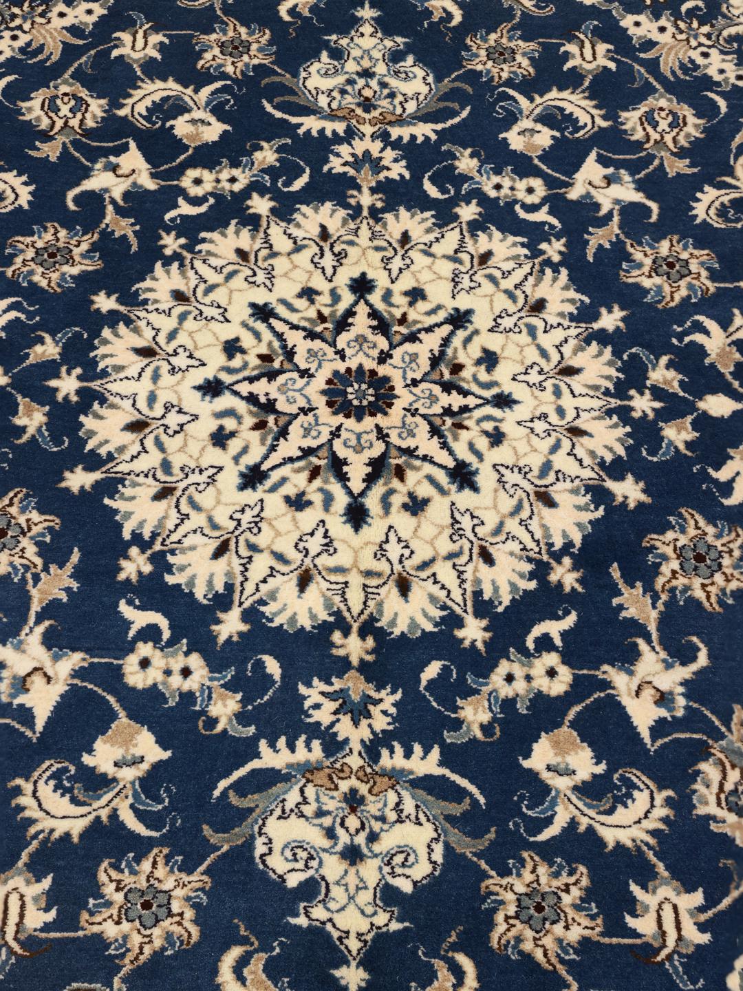 A hand-knotted Nain rug from the Middle East featuring a deep blue field with floral patterns.