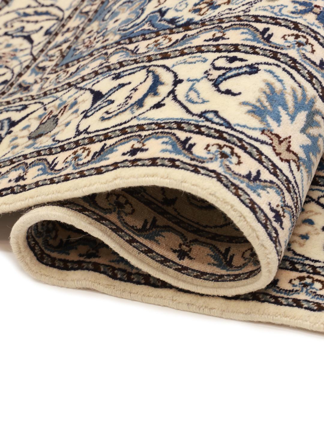 A hand-knotted Nain rug from the Middle East featuring a deep blue field with floral patterns.