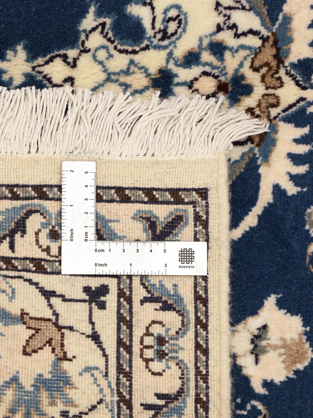 A hand-knotted Nain rug from the Middle East featuring a deep blue field with floral patterns.