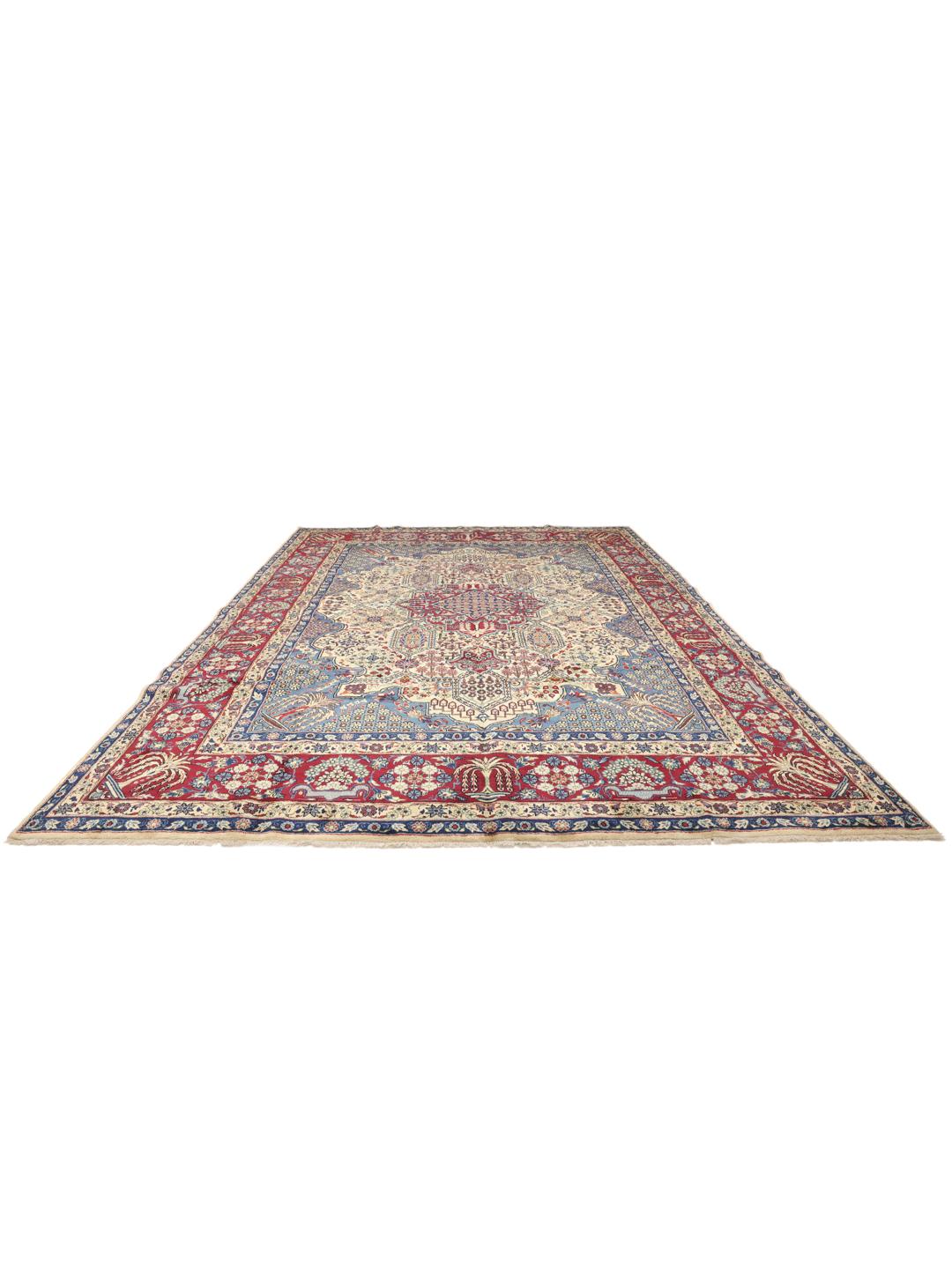 Een groot rechthoekig handgeknoopt Yazd-tapijt uit het Midden-Oosten met een rood en blauw bloemenpatroon.