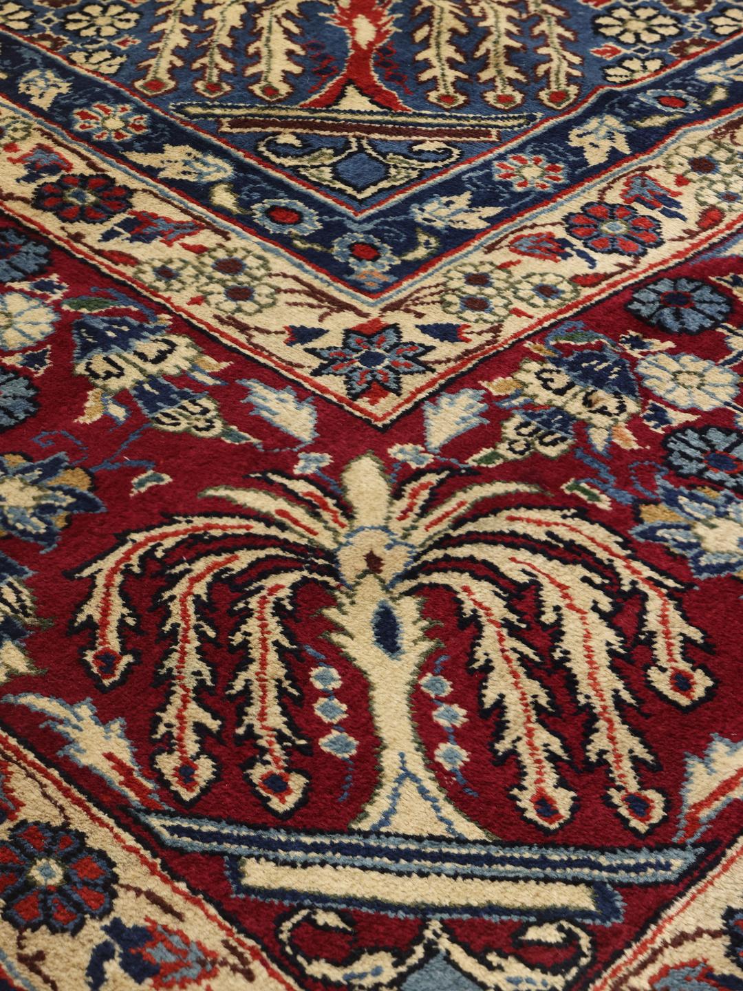Een groot rechthoekig handgeknoopt Yazd-tapijt uit het Midden-Oosten met een rood en blauw bloemenpatroon.
