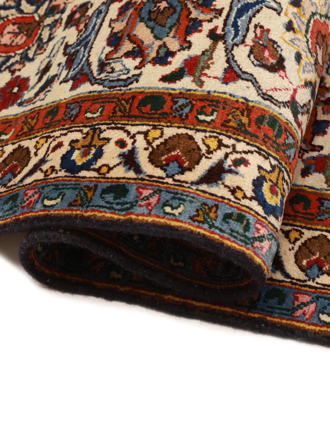 A large, hand-knotted Mashad rug from the Middle East with a dark-blue field and ornate floral medallion in shades of red and blue.