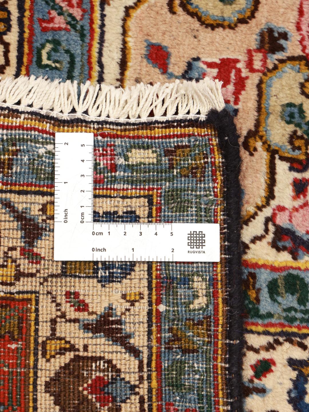A large, hand-knotted Mashad rug from the Middle East with a dark-blue field and ornate floral medallion in shades of red and blue.