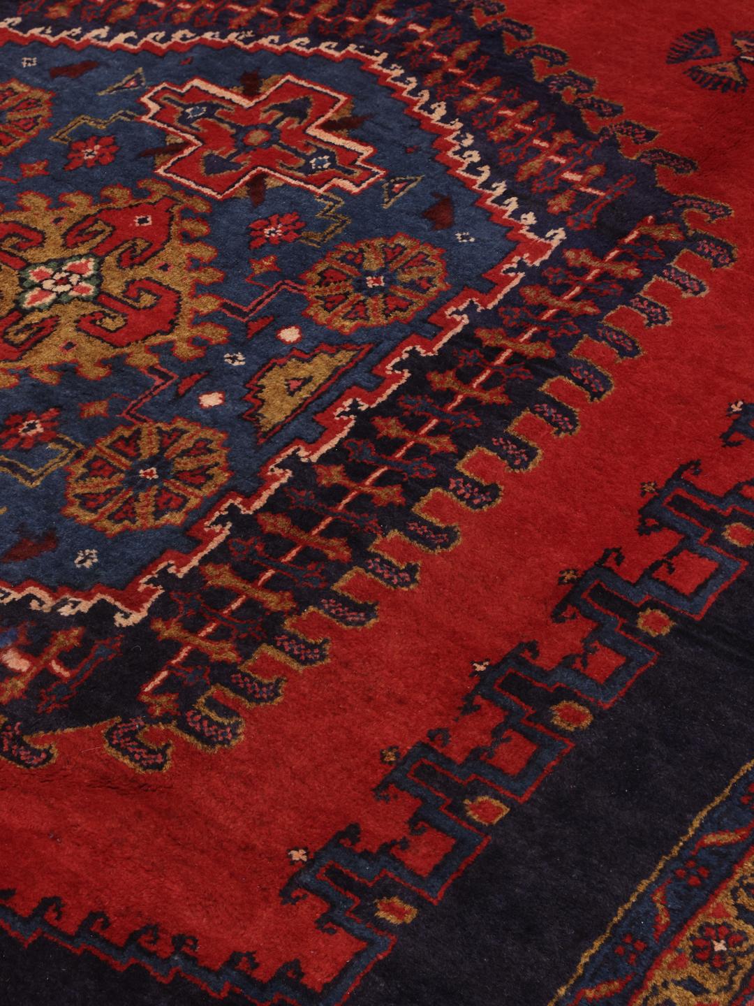 Een handgeknoopt Wiss tapijt uit het Midden-Oosten met een levendig rood en blauw geometrisch patroon.