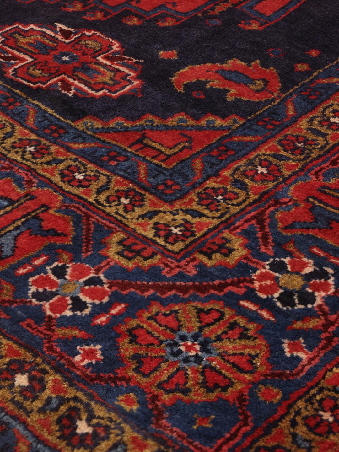 Een handgeknoopt Wiss tapijt uit het Midden-Oosten met een levendig rood en blauw geometrisch patroon.