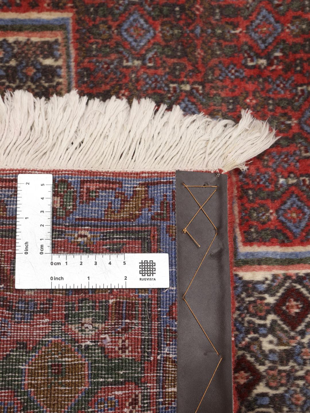 Håndknyttet Senneh-tæppe med et traditionelt medaljondesign i mørkerøde og blå toner.