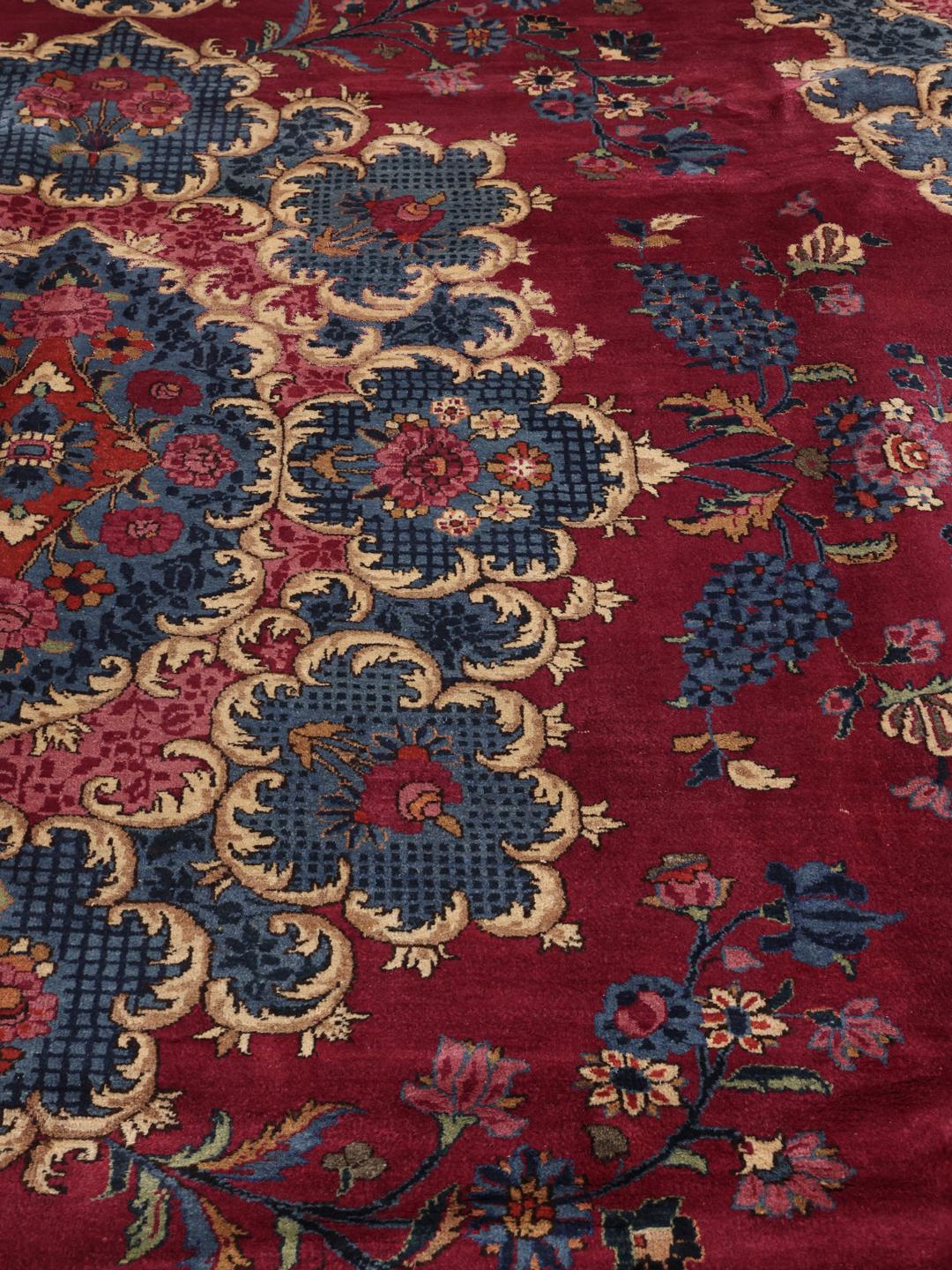 Een groot, handgeknoopt Mashad-tapijt uit het Midden-Oosten met een rood en blauw bloemenpatroon.