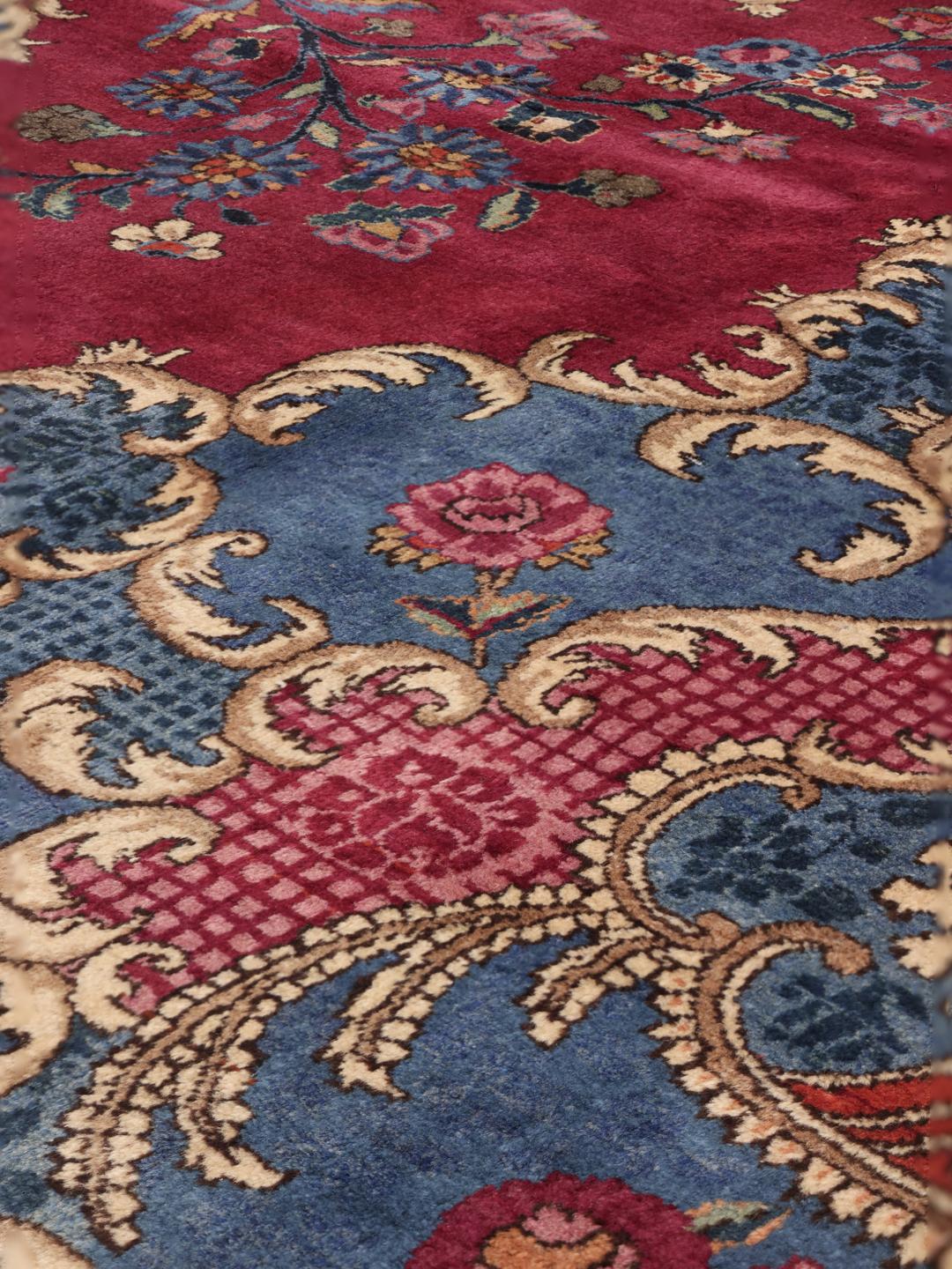 Een groot, handgeknoopt Mashad-tapijt uit het Midden-Oosten met een rood en blauw bloemenpatroon.