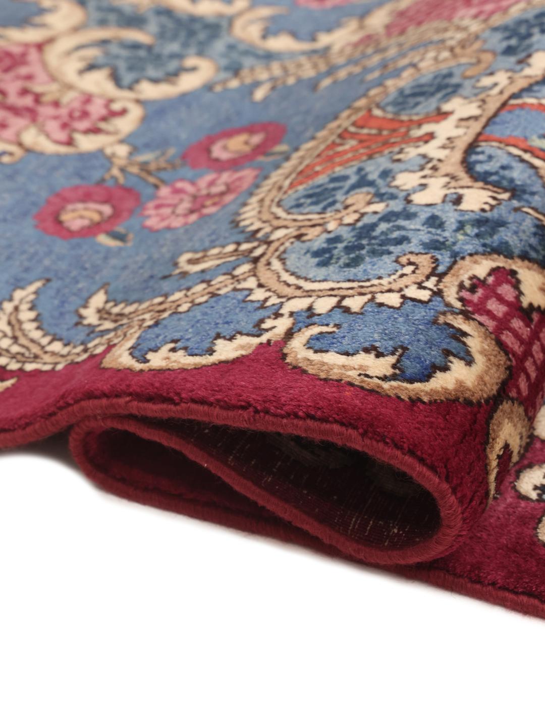 Een groot, handgeknoopt Mashad-tapijt uit het Midden-Oosten met een rood en blauw bloemenpatroon.