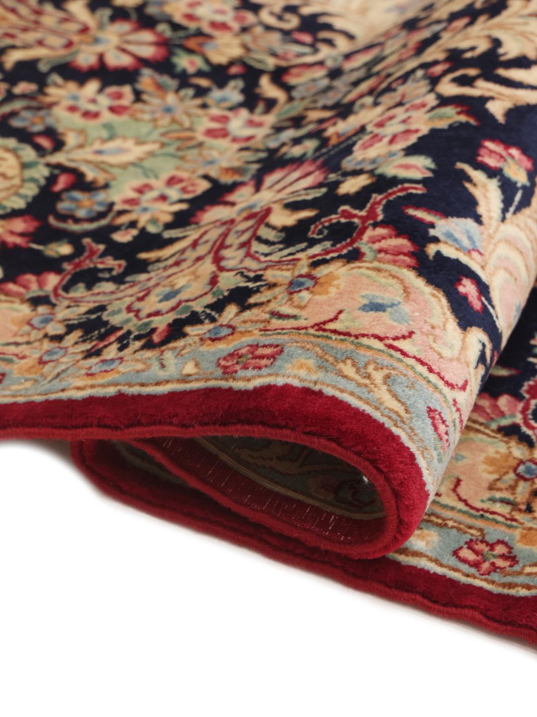 A hand-knotted Kerman rug from the Middle East with a dark-red field and floral patterns.