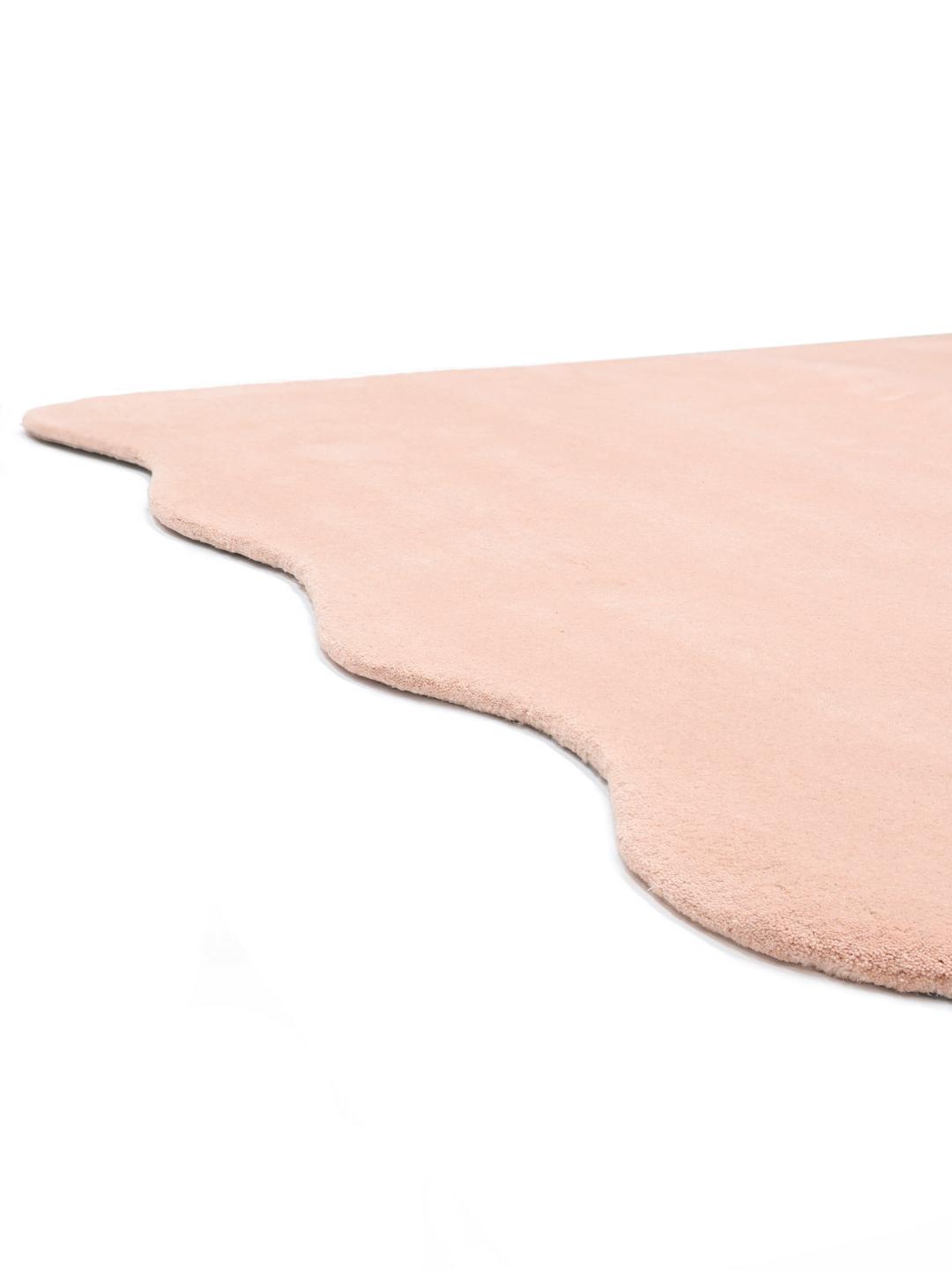 Een zacht roze vloerkleed met een onregelmatige geschulpte vorm