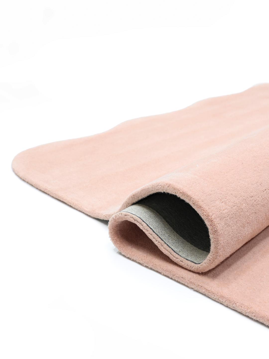 Een zacht roze vloerkleed met een onregelmatige geschulpte vorm