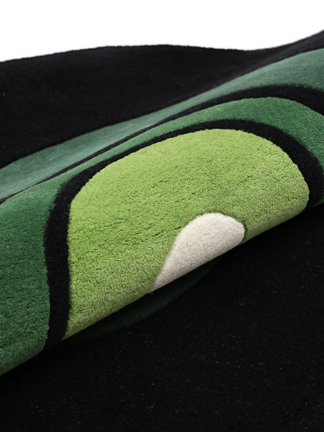 Rond zwart en groen handgetuft vloerkleed met een patroon van concentrische cirkels.