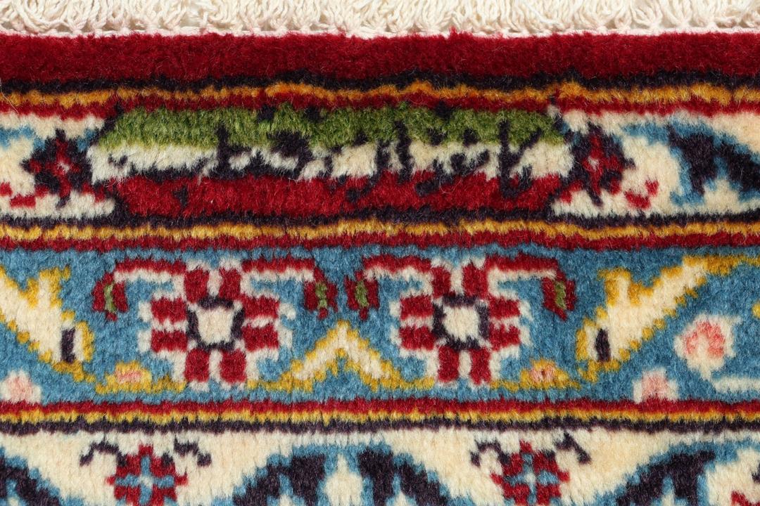 A beautiful red Keshan rug with a central medallion and intricate floral patterns.