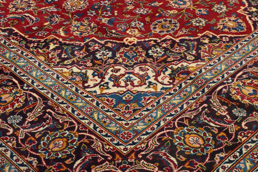 A beautiful red Keshan rug with a central medallion and intricate floral patterns.