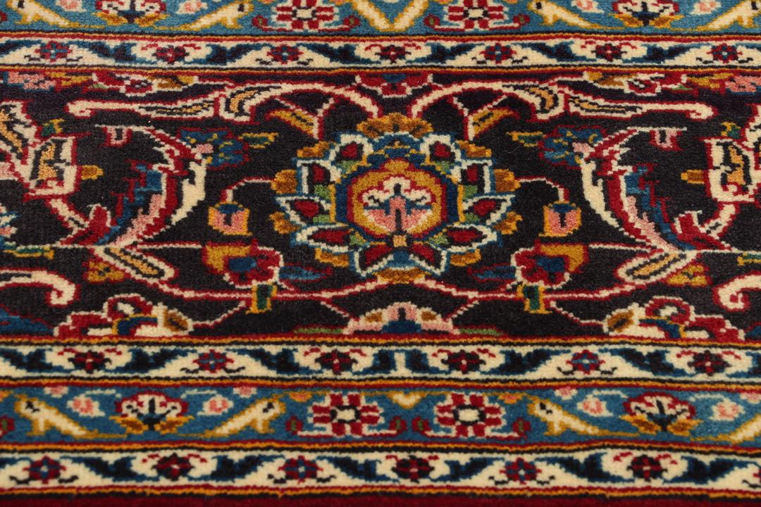 A beautiful red Keshan rug with a central medallion and intricate floral patterns.