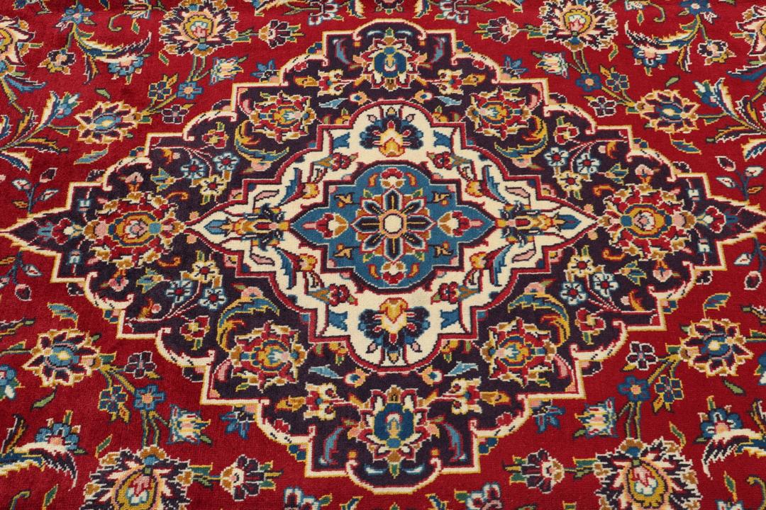A beautiful red Keshan rug with a central medallion and intricate floral patterns.