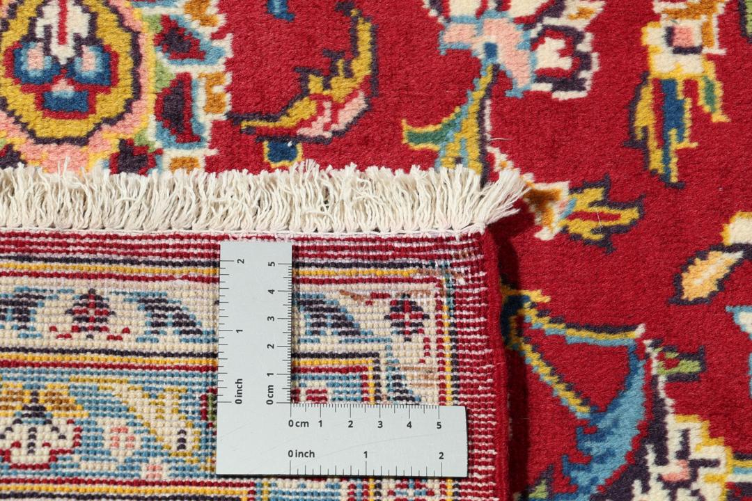 A beautiful red Keshan rug with a central medallion and intricate floral patterns.