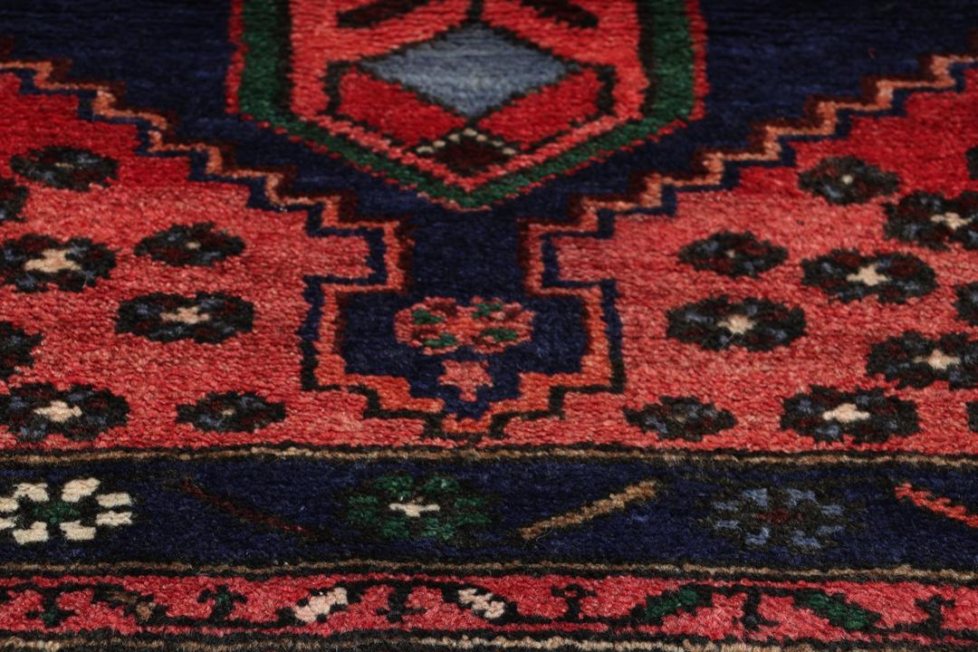 A hand-knotted Hamadan rug from the Middle East featuring a dark-blue and red geometric pattern.