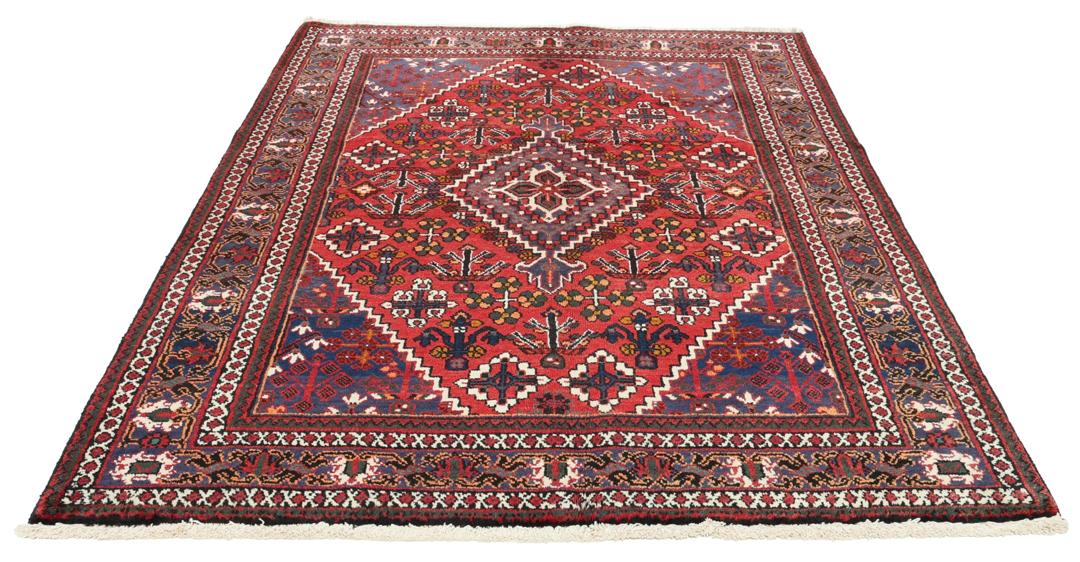 Een handgeknoopt Joshaghan-tapijt uit het Midden-Oosten met een rood en blauw geometrisch medaillonpatroon.
