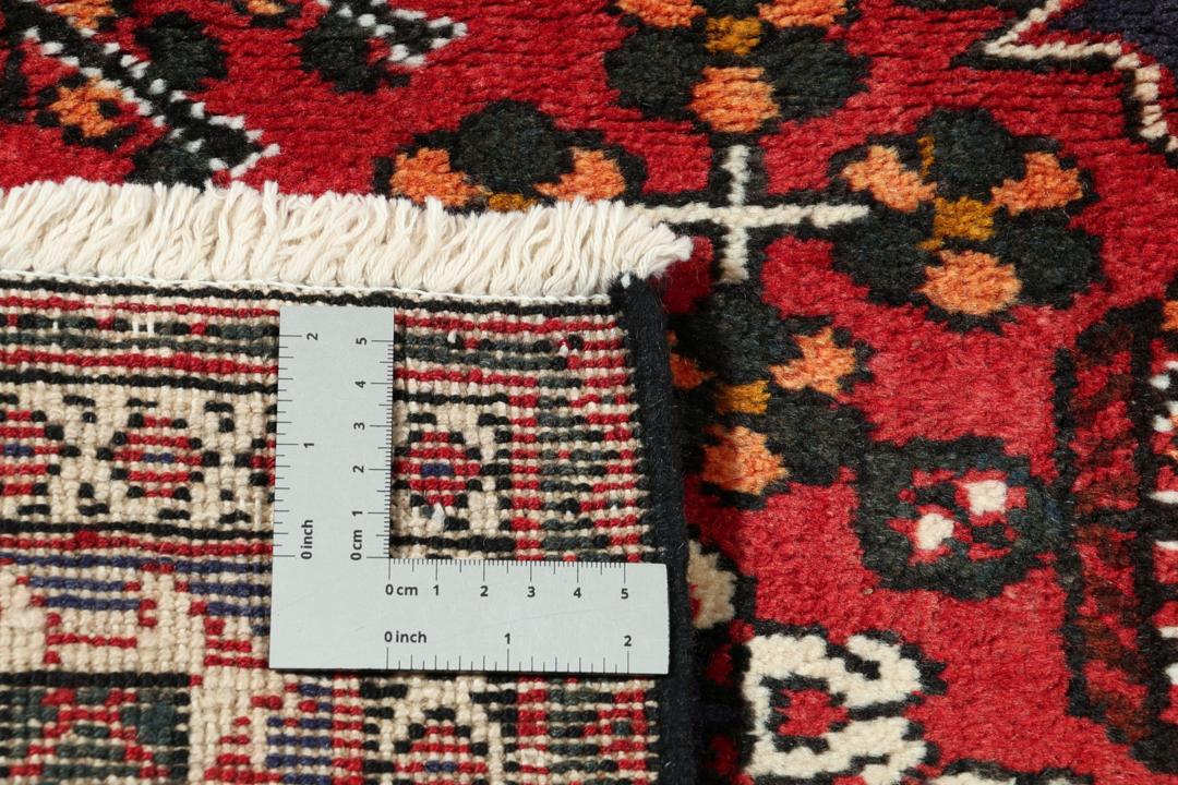 Een handgeknoopt Joshaghan-tapijt uit het Midden-Oosten met een rood en blauw geometrisch medaillonpatroon.