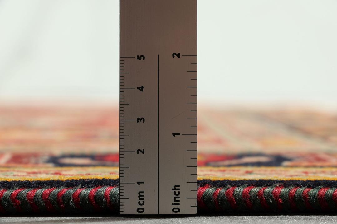 Et håndknyttet Shiraz-tæppe fra Mellemøsten med en levende rød flade og komplekse geometriske mønstre.
