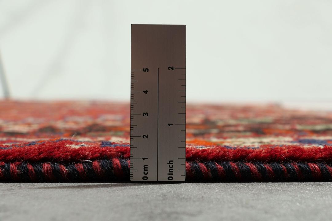 Een handgeknoopt Shiraz-tapijt uit het Midden-Oosten met een levendig rood en donkergrijs palet met geometrische tribale patronen.
