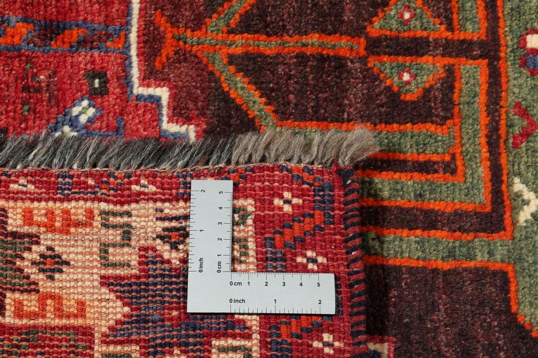 Een handgeknoopt Shiraz-tapijt uit het Midden-Oosten met een levendig rood en donkergrijs palet met geometrische tribale patronen.