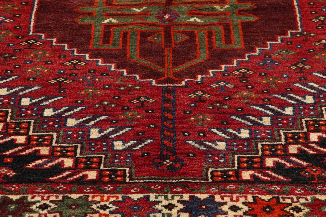 Een handgeknoopt Shiraz-tapijt uit het Midden-Oosten met een levendig rood en donkergrijs palet met geometrische tribale patronen.