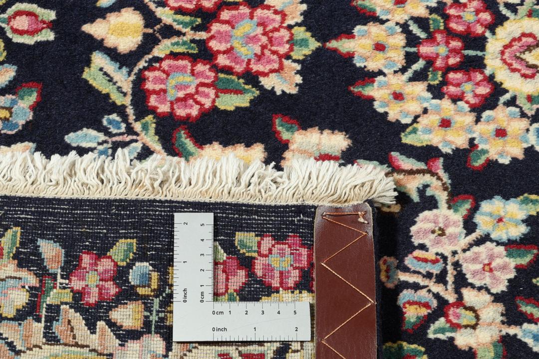 Et håndknyttet Kerman-tæppe fra Mellemøsten med et mørkeblåt felt og blomstermønstre.