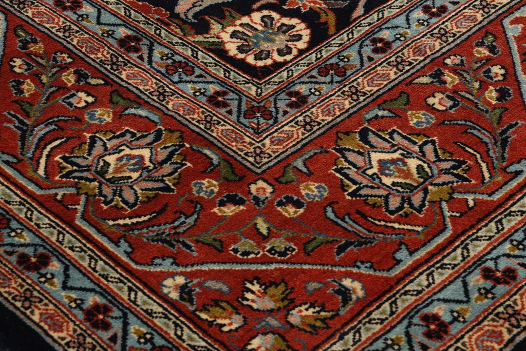 A large rectangular hand-knotted Sarough rug from the Middle East with a dark-blue field and floral patterns.