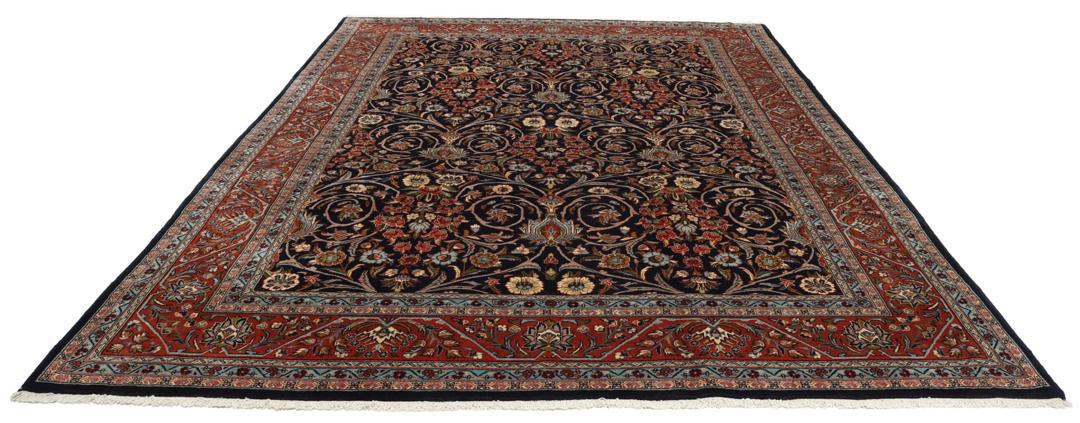 A large rectangular hand-knotted Sarough rug from the Middle East with a dark-blue field and floral patterns.