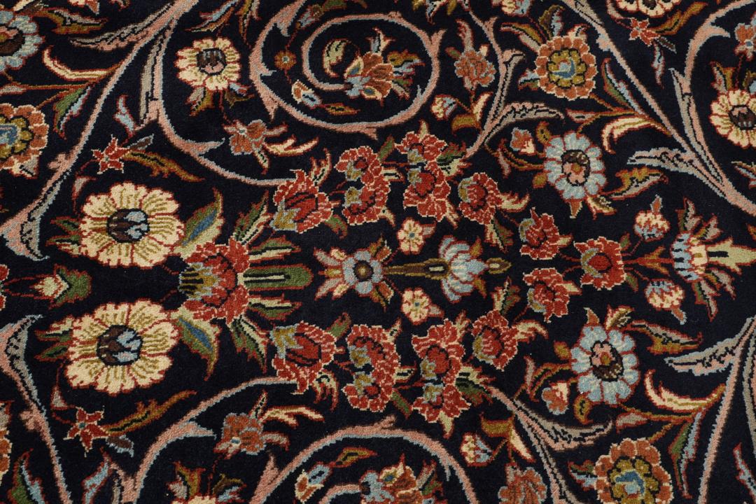A large rectangular hand-knotted Sarough rug from the Middle East with a dark-blue field and floral patterns.