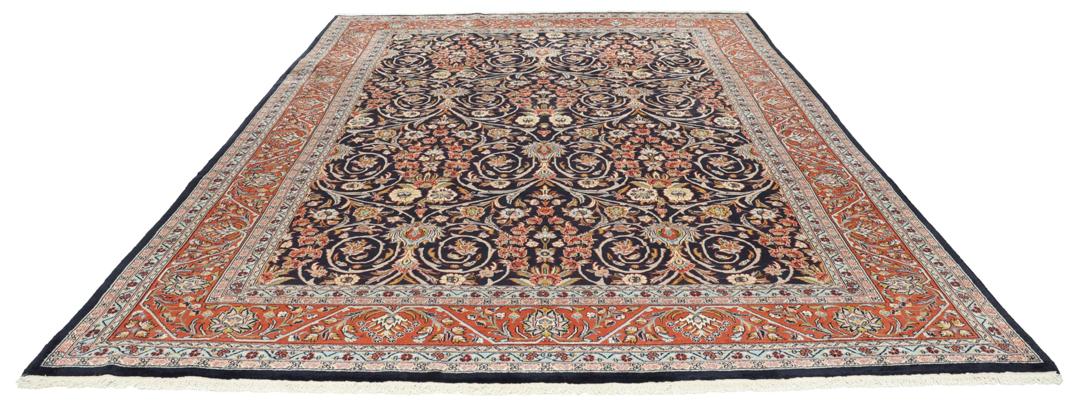 A large rectangular hand-knotted Sarough rug from the Middle East with a dark-blue field and floral patterns.