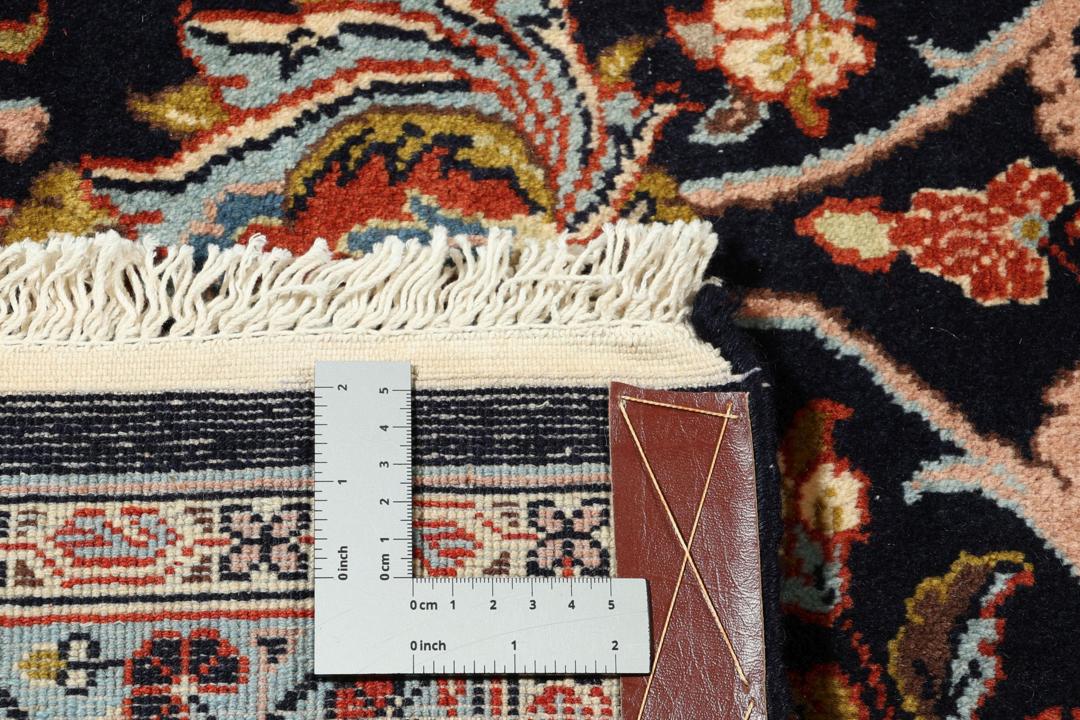 A large rectangular hand-knotted Sarough rug from the Middle East with a dark-blue field and floral patterns.