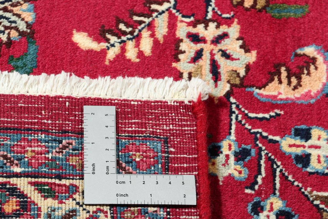 Een groot rechthoekig handgeknoopt Mashad-tapijt uit het Midden-Oosten met een rood veld en verfijnde bloemmotieven.