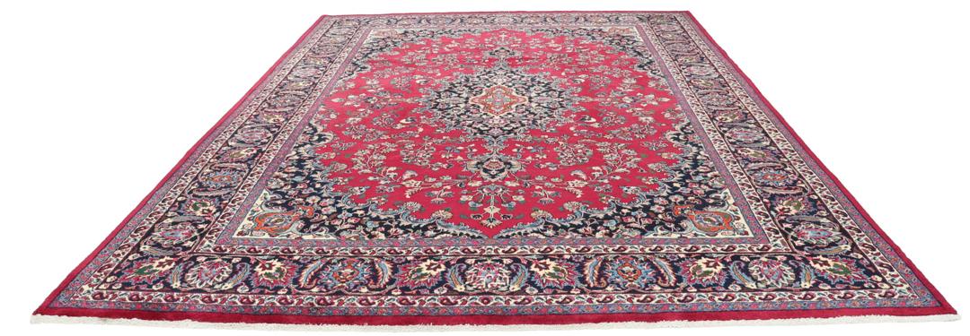 Een groot rechthoekig handgeknoopt Mashad-tapijt uit het Midden-Oosten met een rood veld en verfijnde bloemmotieven.
