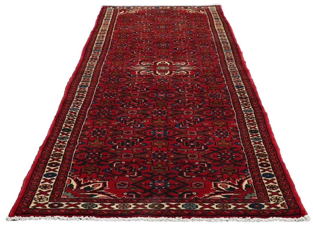 A hand-knotted runner rug from the Middle East featuring a deep red field and geometric motifs