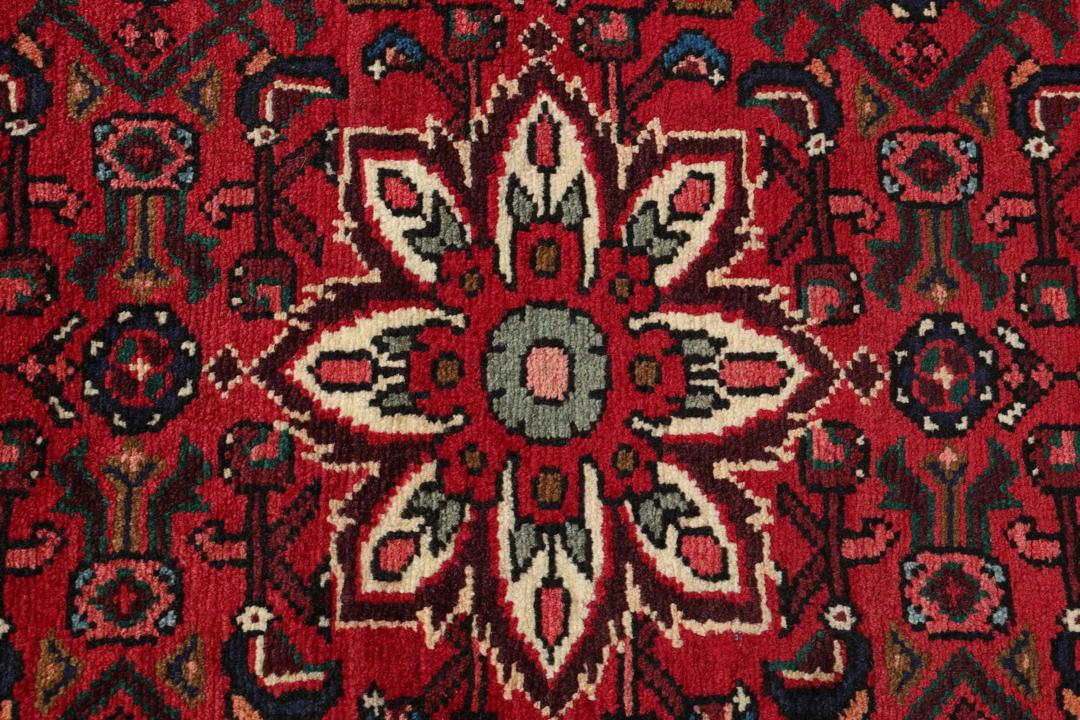A hand-knotted runner rug from the Middle East featuring a deep red field and geometric motifs